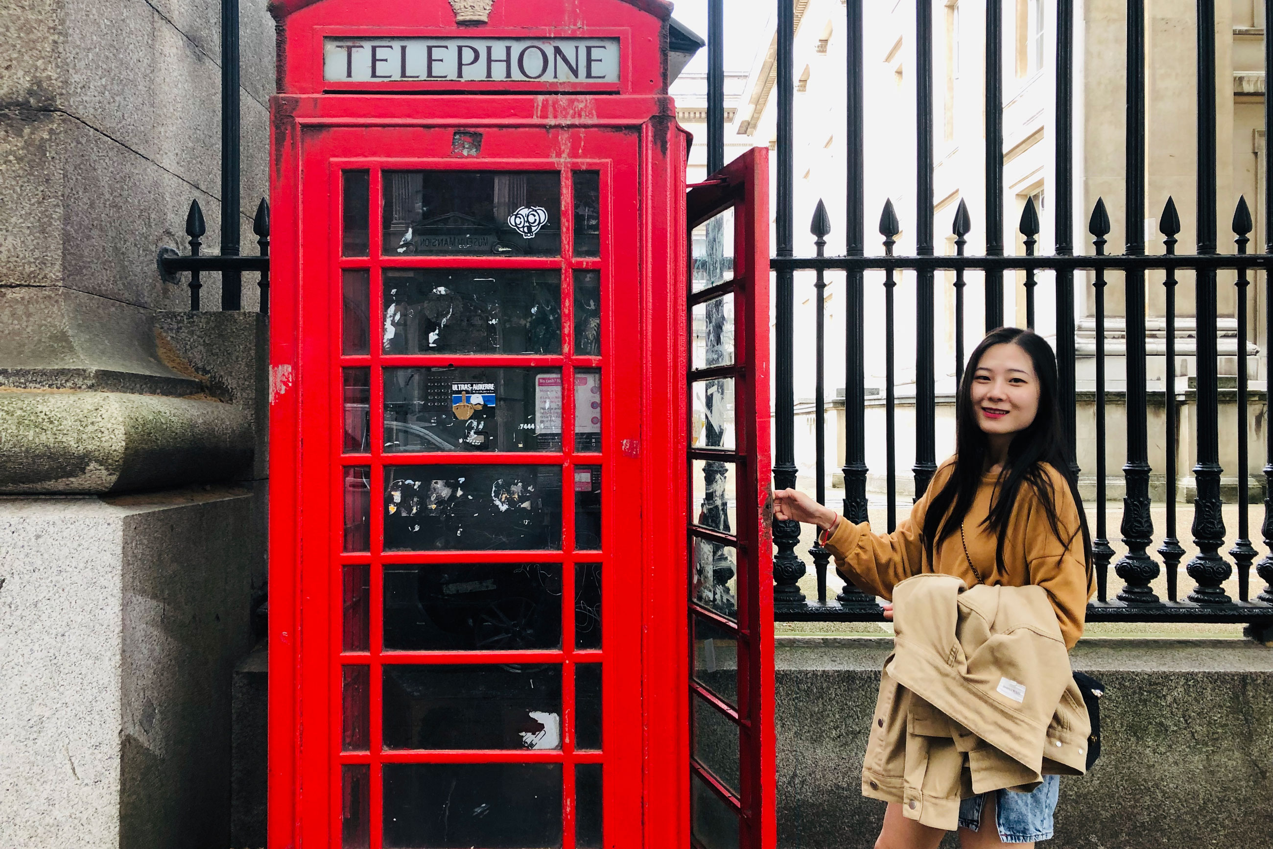 A student posing next to a phone booth.