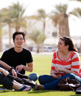 Students seated in the grass at the Qatar campus.