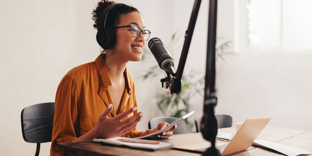A woman wearing headphones speaking into a microphone.