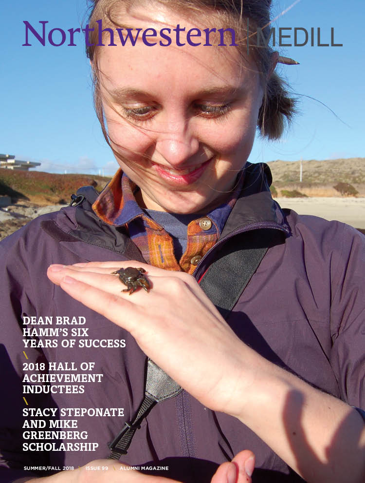 Medill Magazine Issue 99 - a female student holds a crab while reporting from Bodega Bay, California