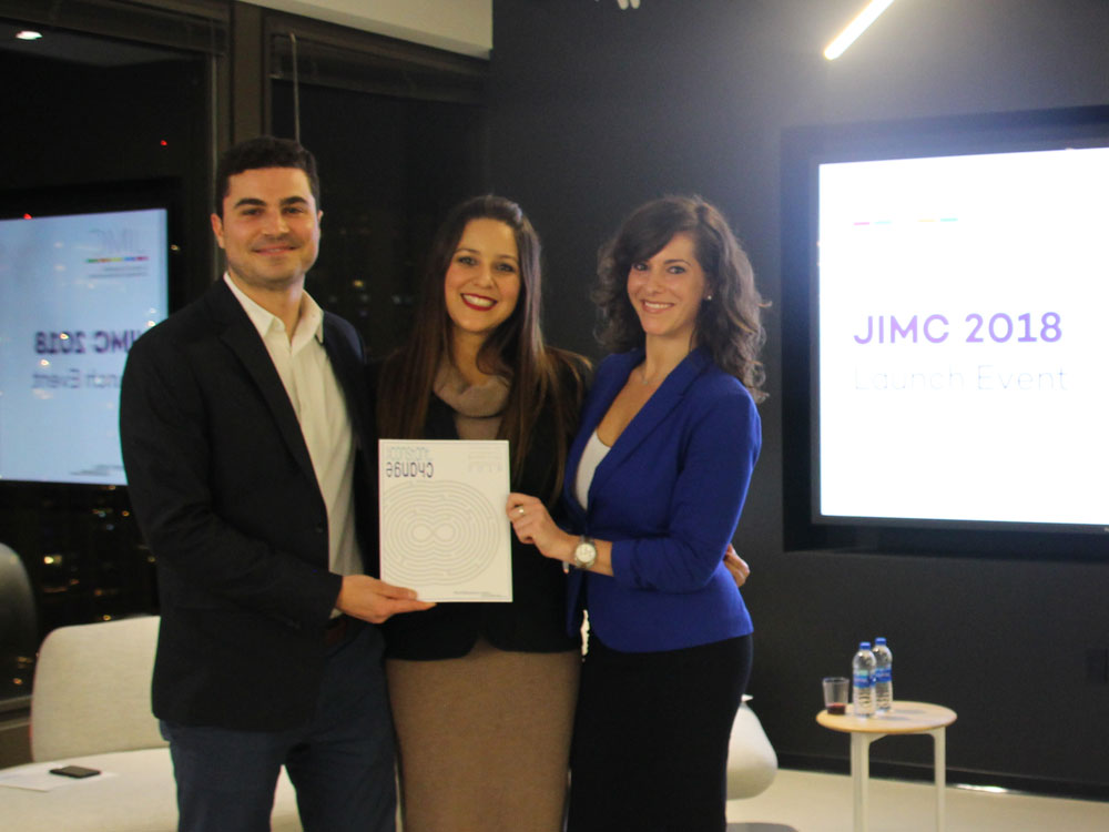 Three students stand together and hold a copy of the new edition of JIMC at the Medill Chicago launch event