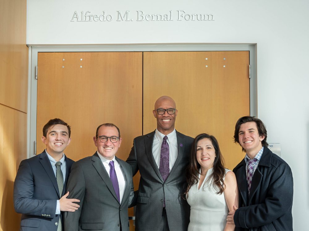 Dean Charles Whitaker and the Vega family pose for a photo in front of the Alfredo M. Bernal Forum entrance.