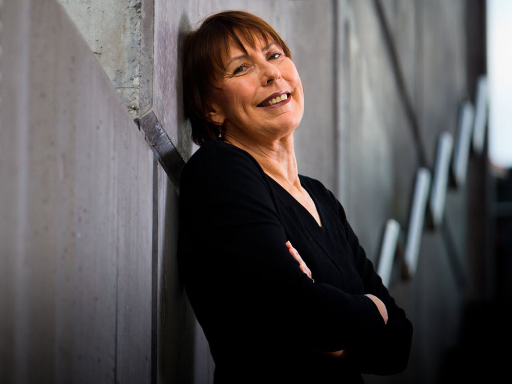 Gayle Kerr leans back against a wall with her arms crossed.