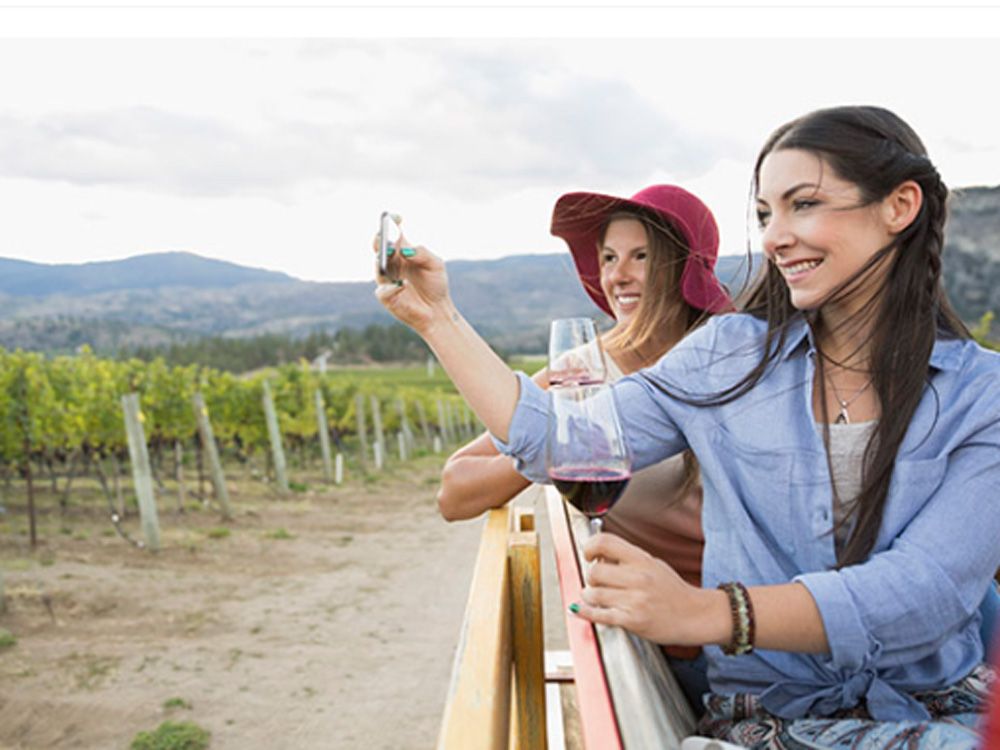 A woman takes a photo on her cell phone at a winery