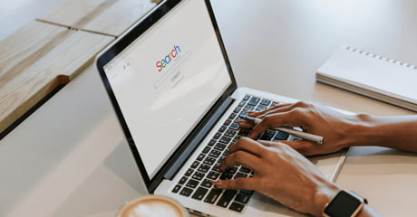 Hands typing on computer showing Google search page