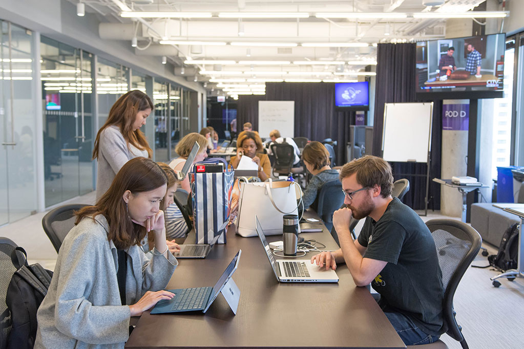 Students work on news stories in a vibrant newsroom.