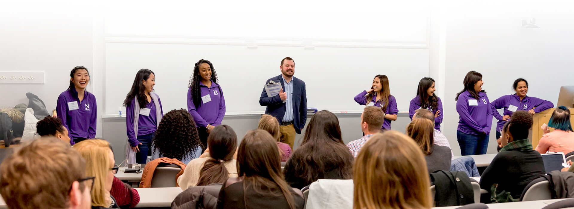 Staff member along with students addressing an audience.