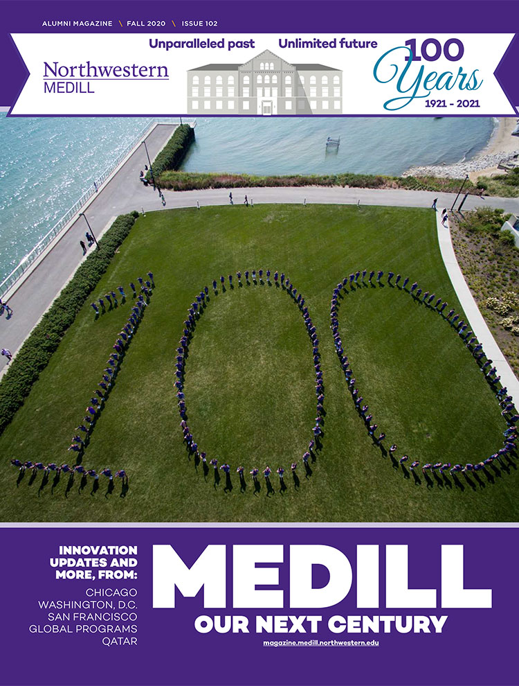 A drone image of students standing in the shape of "100" on an open area of grass by a lake