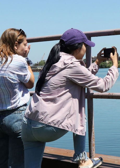 Two women taking photos of a large body of water.