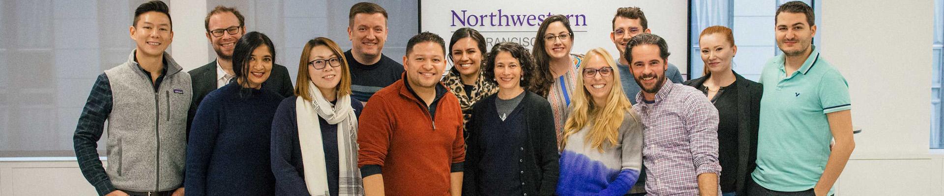 A group of students pose in front of the Northwestern San Francisco sign at the Northwestern San Francisco campus