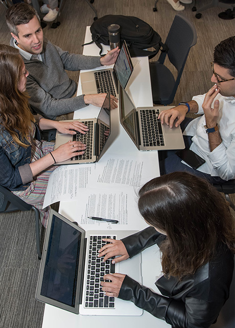 Four professional IMC students working together with laptops