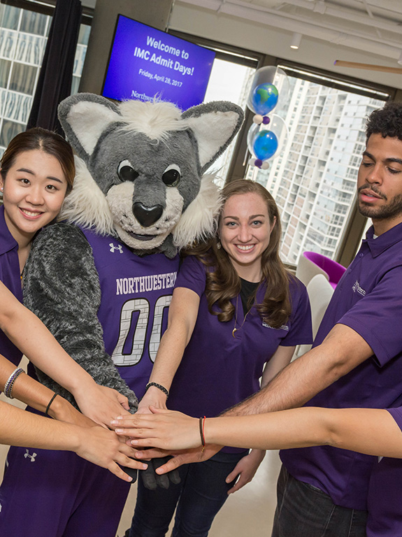 Students raise their hands in excitement with Willie the Wildcat