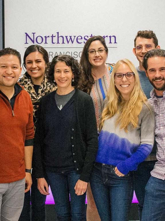 A group of students pose in front of the Northwestern San Francisco sign at the Northwestern San Francisco campus