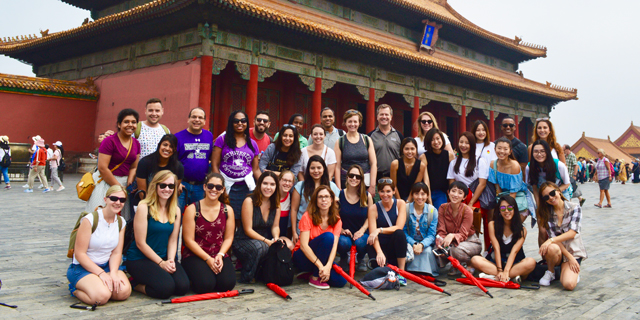 Students and faculty pose for a photo in front of the Great Wall of China