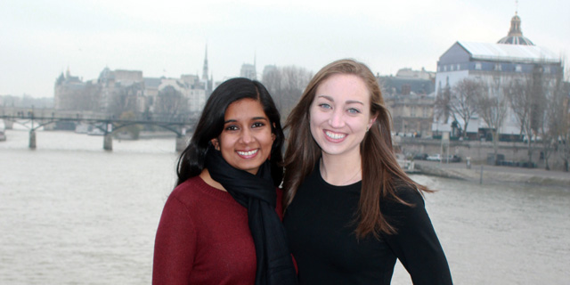 Two students pose for a photo in front of the Seine river in Paris