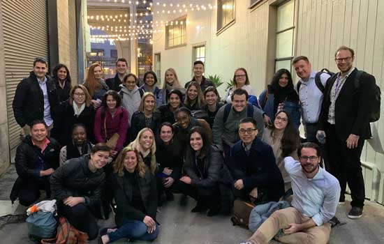 A large group of students pose for a photo outside when they visited the IDEO office in San Francisco