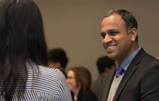 An IMC faculty member wearing a suit talks with a student