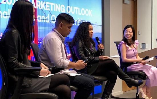 Four alumni sit at the front of a room in chairs and talk to an audience; the Golden Gate Bridge is pictured on a slide in the background