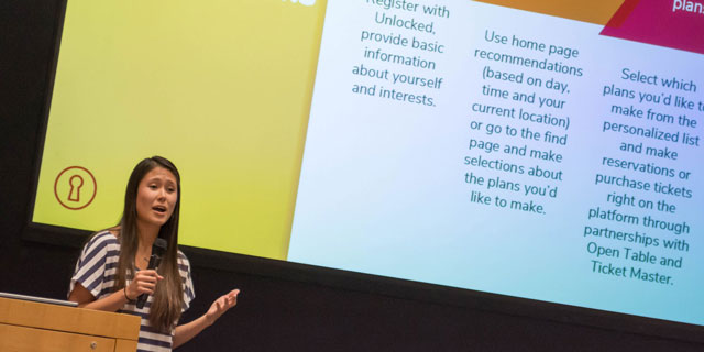 A student speaks while standing in front of colorful presentation