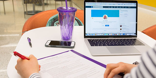 A student working on a résumé, with a laptop open to LinkedIn. 