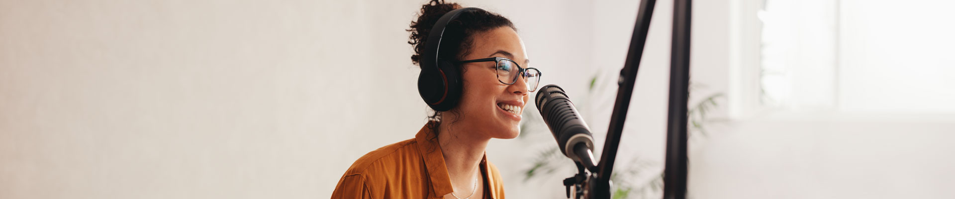 A woman wearing headphone speaking into a microphone.