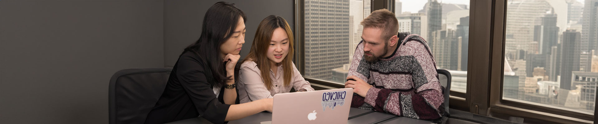 Students in an office looking at a laptop together.