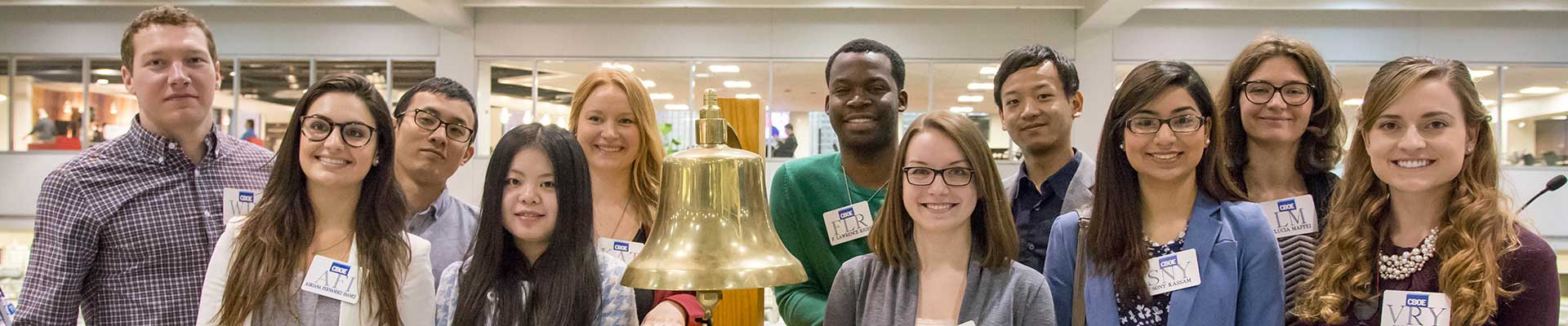A group of students next to a bell.
