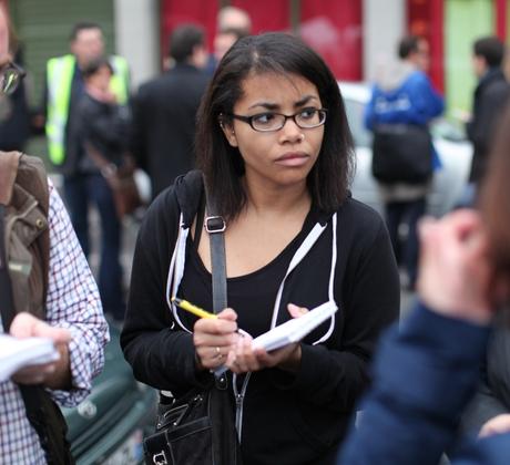 A student on the street writing in her notebook.