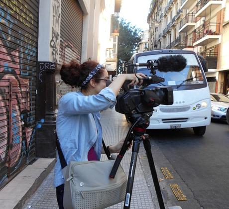 A student standing behind a camera and tripod.