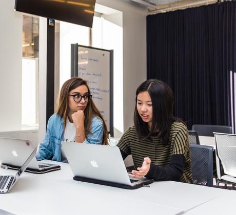 Two students working together on a laptop.