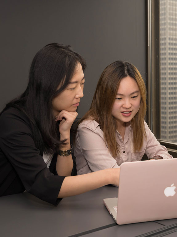 Students in an office looking at a laptop together.