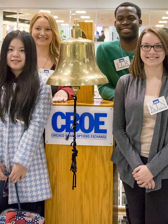 A group of students next to a bell.