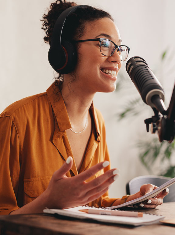 A woman wearing headphone speaking into a microphone.