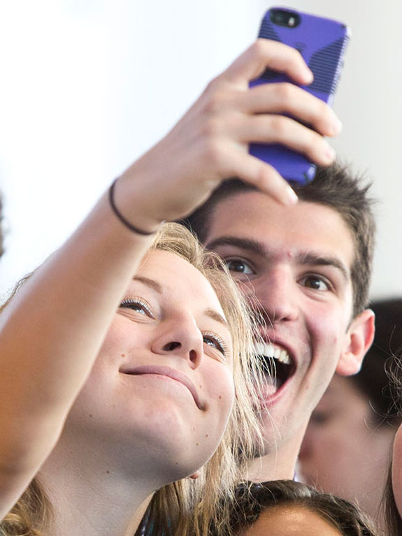 Student smiling and taking a selfie in a group.