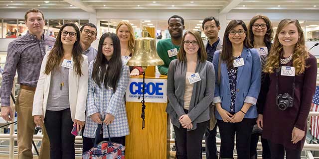 A group of students standing next to the Chicago Board Options Exchange bell.
