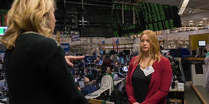 A student stands in front of a stock exchange.