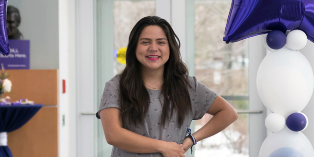 A student in the Accelerated Master’s Program poses for a photo in a hallway by balloons.