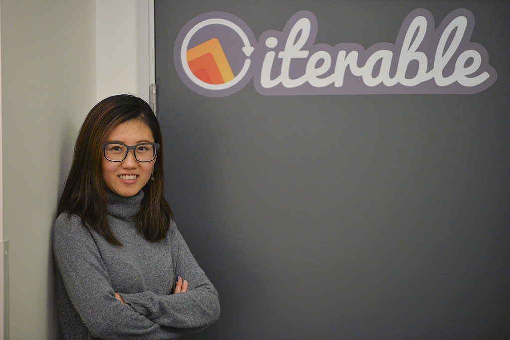 Ashley Zhang in front of a sign that says Iterable.