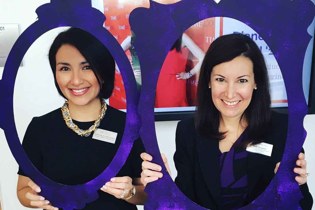 Two members of the Medill staff and faculty smiling while holding purple frames.