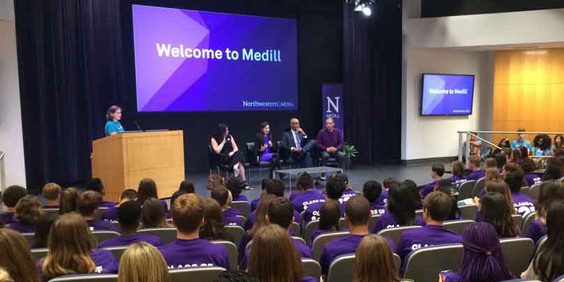 Students listen to faculty in an auditorium during a orientation event.