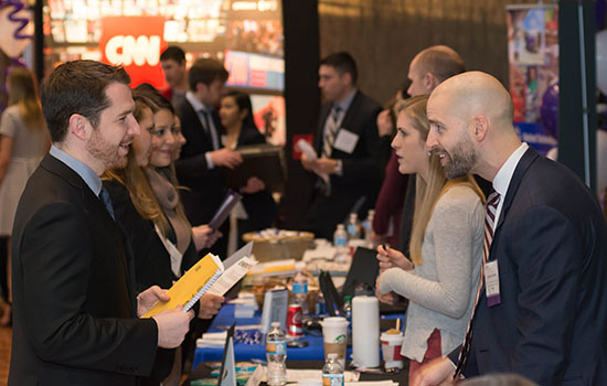 Group of people standing and talking at career fair