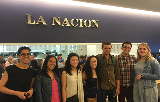 Students standing in front of a sign that says "La Nacion".