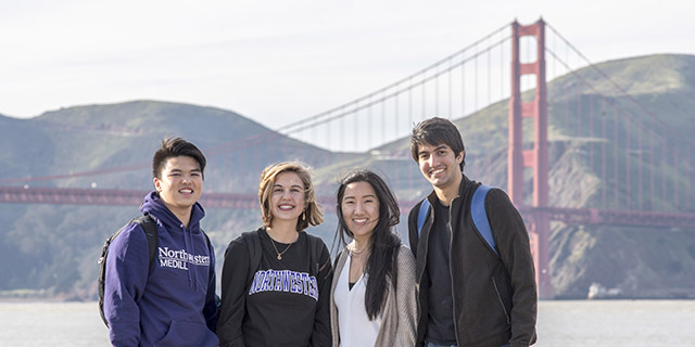 Students wearing Northwestern apparel smile with the Golden Gate Bridge in the background.