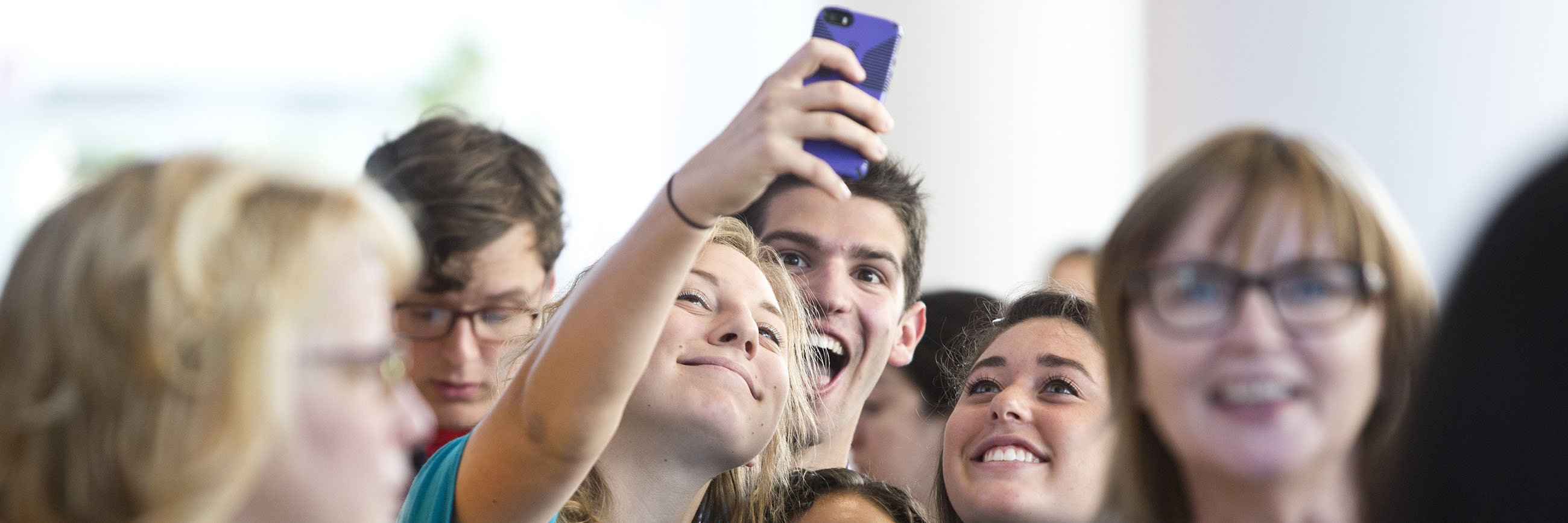 Student smiling and taking a selfie in a group.