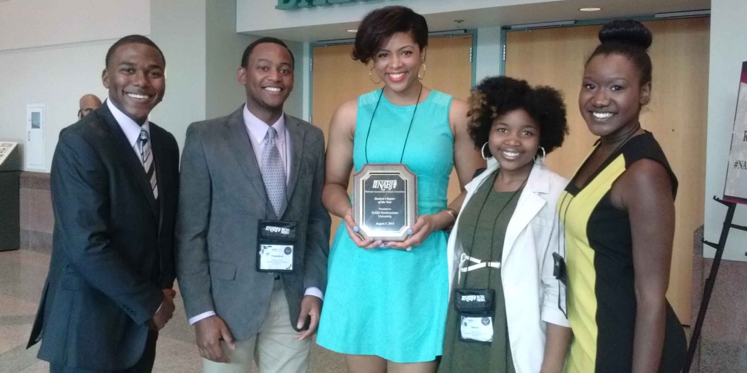 People at a conference hold up awards.