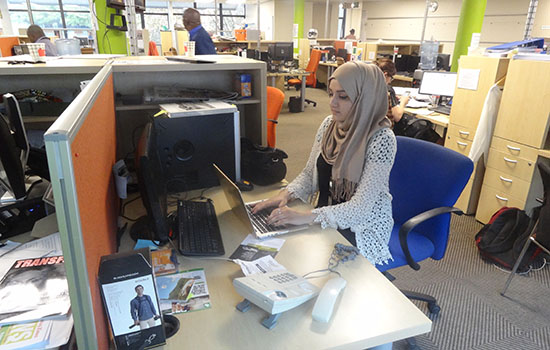 Student working at a computer in a newsroom.