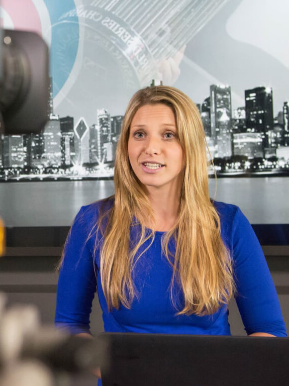 A woman seated at an anchor desk