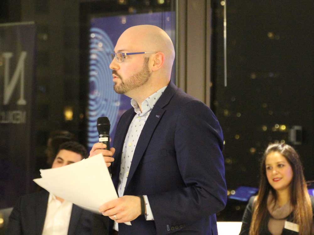 A man holds a microphone and speaks to a group of people