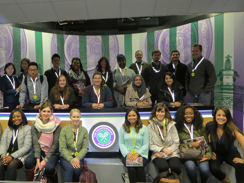 A large group of students sit at a desk at Wimbledon in London