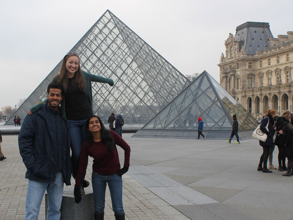 Three Medill IMC students pose for a photo in front of the Louvre Museum in Paris